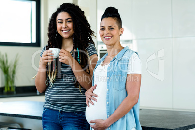 Portrait of pregnant lesbian couple standing together