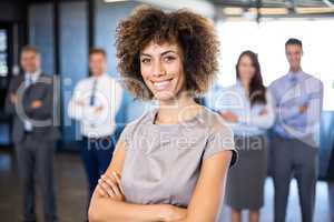 Businesswoman smiling at camera while her colleagues standing in