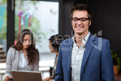 Smiling man and people using laptop