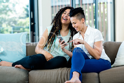 Lesbian couple looking at mobile phone and smiling