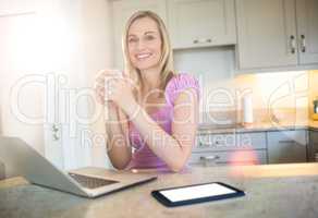 Pretty blonde woman having coffee and using laptop