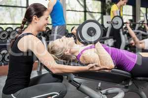 Smiling woman working out with dumbbells with female trainer