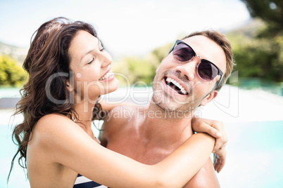 Young couple cuddling each other near pool