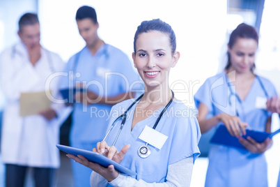 Female doctor using tablet and smiling at camera