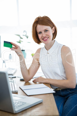 smiling hipster business woman holding up a credit card