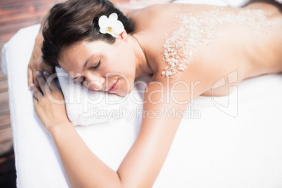 Woman lying on massage table with salt scrub on back