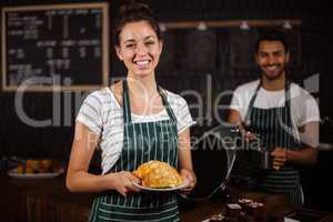 Smiling barista holding croissants