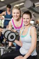 Trainer woman helping woman lifting dumbbell