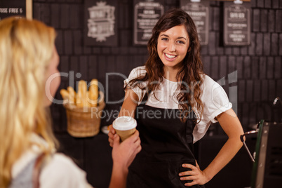 Pretty waitress giving cup of coffee to customer