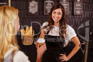 Pretty waitress giving cup of coffee to customer