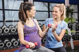 Trainer helping pregnant woman at the gym