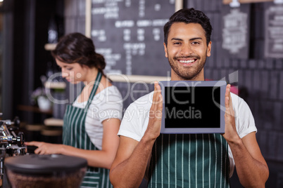 Smiling barista showing tablet at the camera Smiling barista showing tablet at the camera