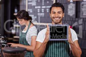 Smiling barista showing tablet at the camera