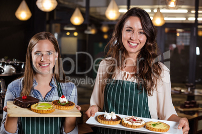 Smiling baristas holding desserts