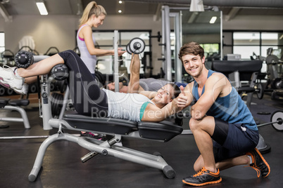 Trainer man helping woman doing her crunches and showing thumbs