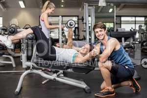 Trainer man helping woman doing her crunches and showing thumbs