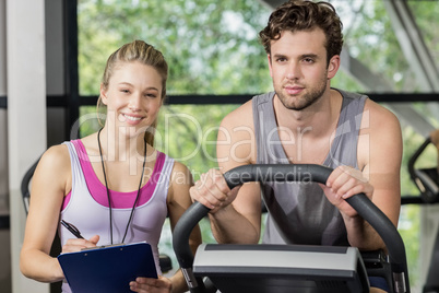 Trainer woman with a man doing exercise bike