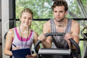 Trainer woman with a man doing exercise bike