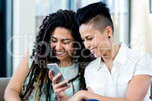 Lesbian couple looking at mobile phone and smiling
