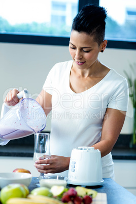 Pregnant woman pouring smoothie in glass