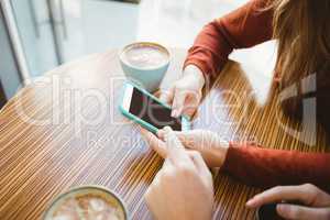 Friends using smartphone and having coffee