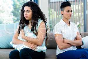 Unhappy lesbian couple sitting on sofa