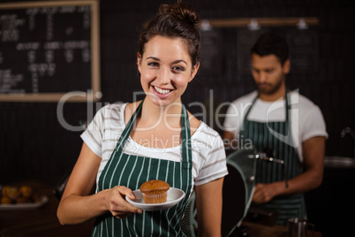 Smiling barista holding muffin