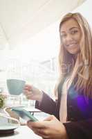 Woman using her smartphone and drinking coffee