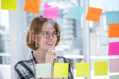 smiling hipster woman sticking notes on a notice board