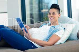 Portrait of pregnant woman relaxing on sofa with her digital tab
