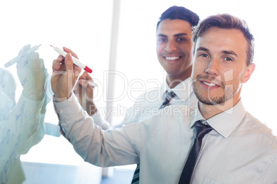 Businesspeople writing on white board