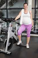 Pregnant woman standing next to exercise bike