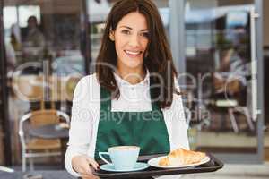 Waitress holding tray with coffee and croissant