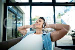 Pregnant woman listening to music on sofa