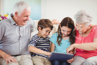 Senior couple using digital tablet with their grand children