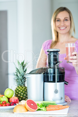 Blonde woman holding a smoothie glass in the kitchen