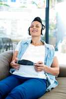 Pregnant woman listening to music on sofa