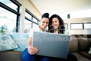 Lesbian couple smiling while using laptop