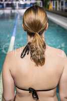 Rear view of woman sitting on the edge of the pool
