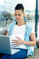 Pregnant woman relaxing on sofa with her laptop