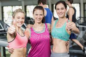 Athletic smiling women posing with thumbs up