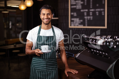 Smiling barista holding a cup of coffee