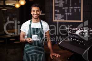 Smiling barista holding a cup of coffee