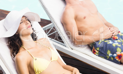 Young couple sitting on sun loungers
