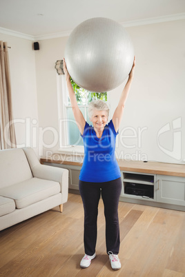 Senior woman lifting exercise ball while exercising Senior woman lifting exercise ball while exercising