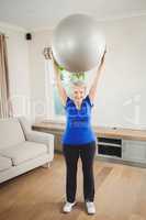 Senior woman lifting exercise ball while exercising