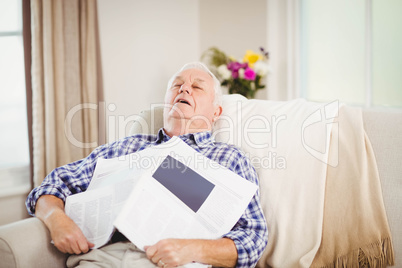 Senior man relaxing on sofa with newspaper