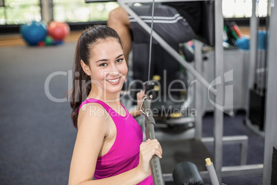 Fit woman using weight machine