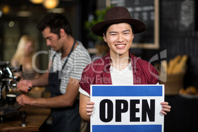 Portrait of a asian waiter showing open sign