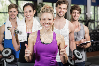 Fitness group lifting dumbbells and showing thumbs up